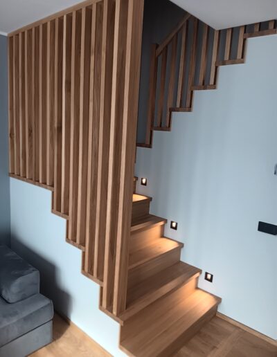 Modernne täispuidust trepp vertikaalse piirde ja astmete LED-valgustusega.